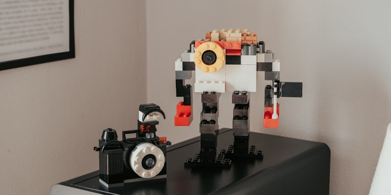 a lego robot sitting on top of a table next to a camera