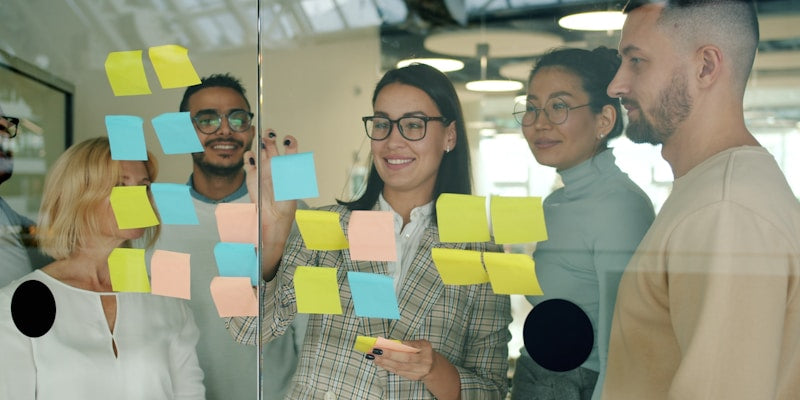Team collaborating with sticky notes on glass wall
